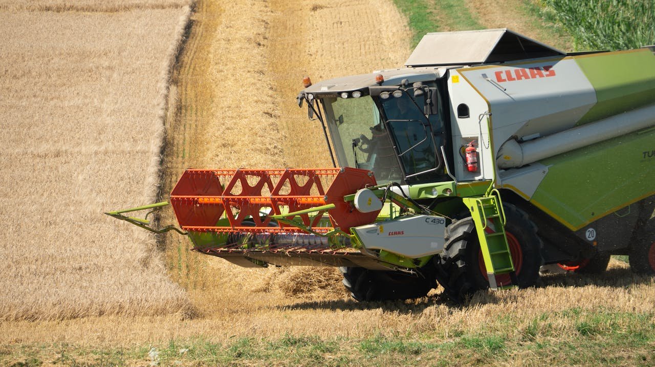 Offerings A combine harvester collecting wheat in a sunny countryside field, showcasing agricultural machinery in action.